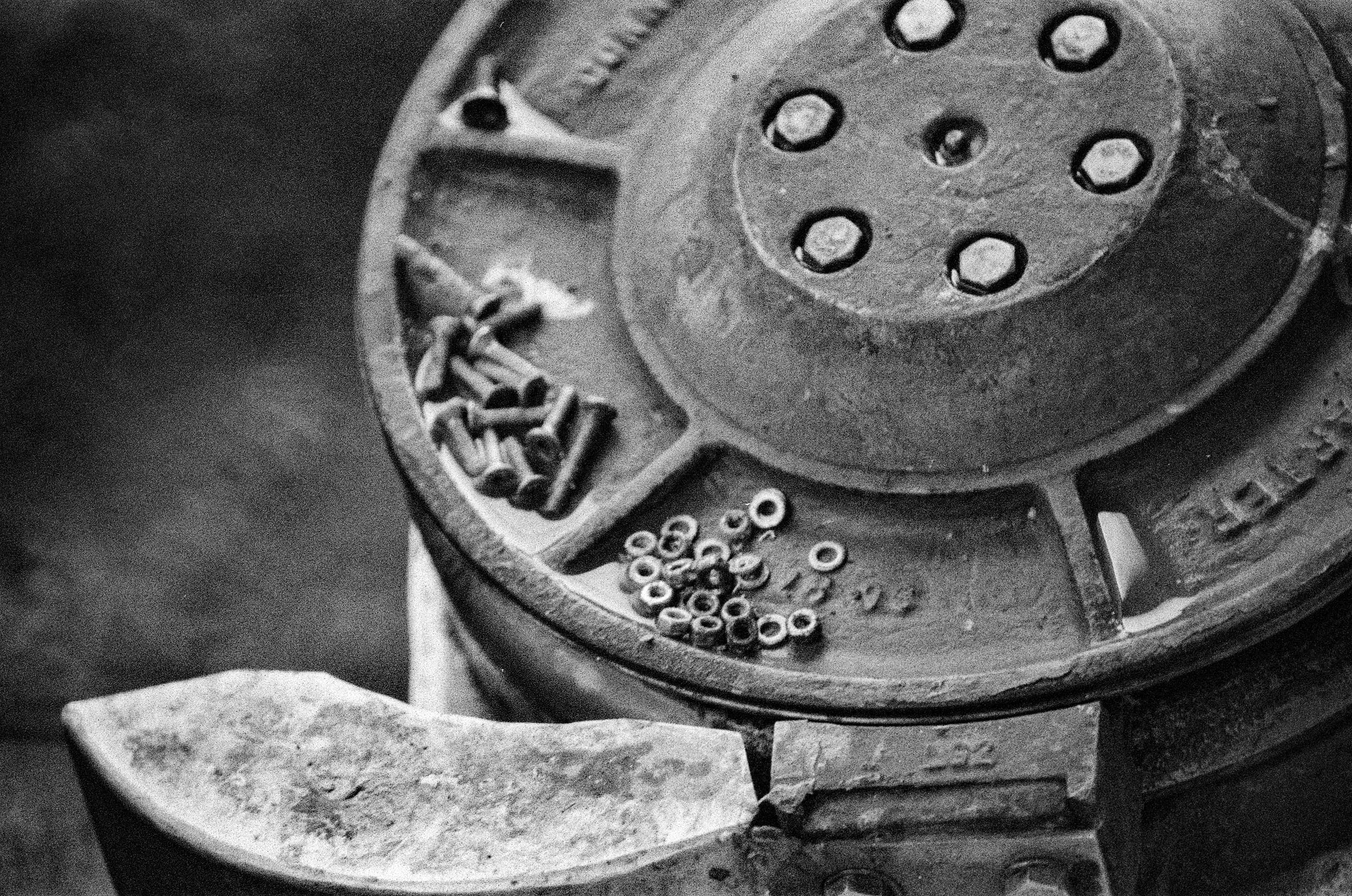Gros plan de pièces mécaniques industrielles vintage avec engrenages et boulons épars, macro argentique noir et blanc